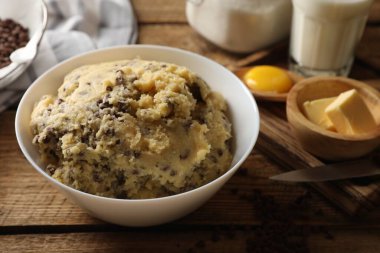 Çikolatalı kurabiye hamuru kasede ve malzemeler beyaz ahşap masada, yakın plan.