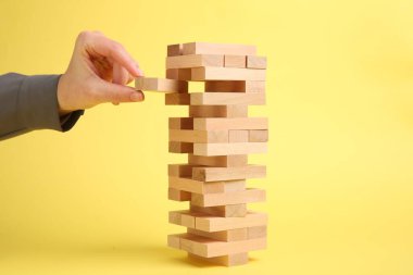 Sarı arka planda Jenga kulesi oynayan kadın, yakın plan.