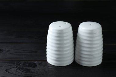 Siyah ahşap masada biber ve tuzluk, yakın plan. Metin için boşluk