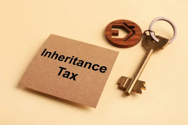 Inheritance Tax. Card and key with key chain in shape of house on beige background, closeup