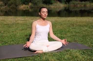 Güzel bir kadın dışarıda yoga yapıyor. Lotus pozu