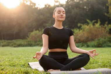 Güneşli bir günde dışarıda yoga yapan güzel bir kadın. Lotus pozu