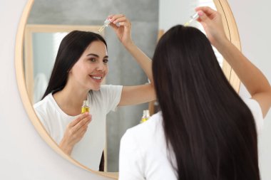 Güzel bir kadın banyoya saç serumu sürüyor. Kozmetik ürünü