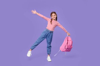 Menekşe arka planda sırt çantası olan mutlu bir kız öğrenci.