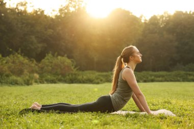 Güzel bir kadın dışarıda yoga yapıyor.