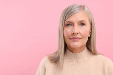 Pembe arka planda orta yaşlı güzel bir kadının portresi, metin için boşluk