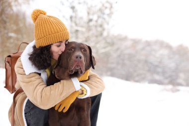 Karlı parkta Labrador Retriever köpeği olan bir kadın. Mesaj için yer var.
