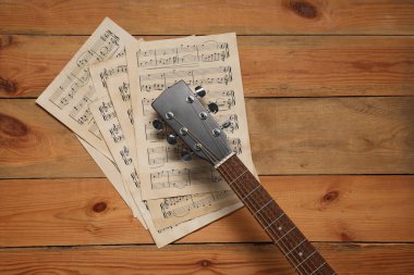 Kağıt kağıtlar, notalar ve akustik gitarla ahşap masa, üst manzara.