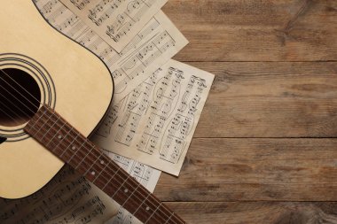 Kağıt kağıtlar, notalar ve akustik gitarla ahşap masa, üst manzara. Metin için boşluk