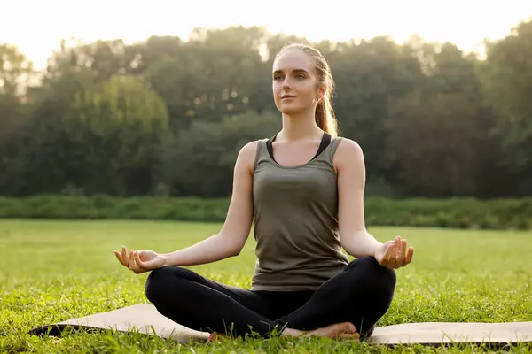 Güzel bir kadın dışarıda yoga yapıyor. Lotus pozu