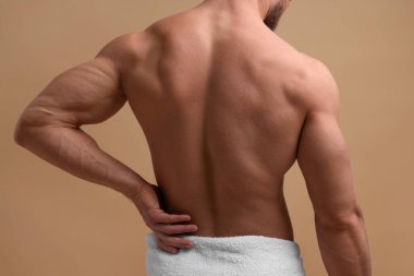 Man suffering from back pain on beige background, closeup clipart