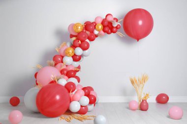 Beyaz duvarın yanında balon çelenk var. Şenlik Dekoru