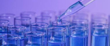 Laboratuvar analizi. Menekşe arkaplanındaki test tüpüne reaktör damlatılıyor. Yakın plan. Pankart tasarımı