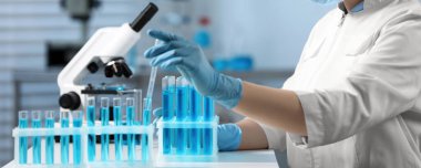 Laboratuvar analizi. Bilim adamı, kapalı bir masadaki deney tüpünden numune alıyor. Yakın plan. Pankart tasarımı