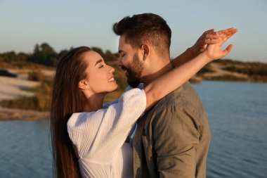 Gün batımında nehrin kenarında dans eden güzel bir çift
