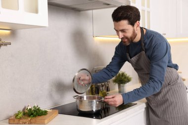 Adam mutfaktaki ocakta çorba pişiriyor.