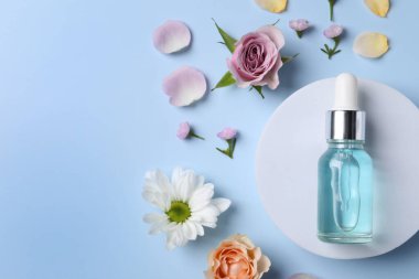 Bir şişe kozmetik serumu, açık mavi arka planda güzel çiçekler ve taç yaprakları. Metin için boşluk