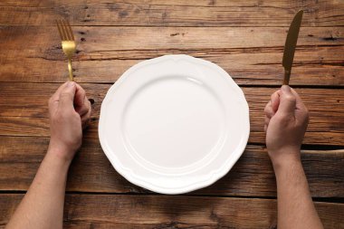 Elinde çatal bıçak takımı ve boş tabak olan adam, yakın plan.