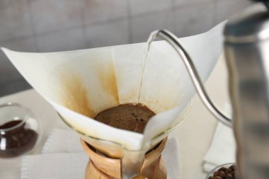 Damlalı kahve yapıyorum. Masada kağıt filtresi olan kimya kahve makinesine sıcak su dökmek.