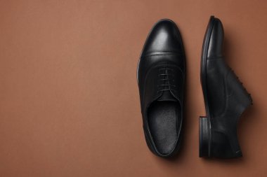 Kahverengi arka planda bir çift deri adam ayakkabısı, üst manzara. Metin için boşluk