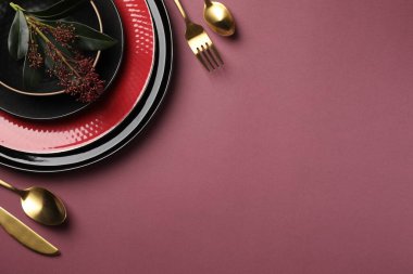 Pembe arka planda çatal bıçak takımı ve çiçek dekoru olan şık bir masa. Metin için boşluk