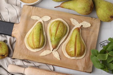 Board with raw dough, fresh pears and mint on white tiled table, flat lay clipart