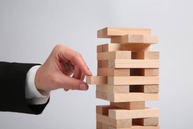Açık gri arka planda Jenga oynayan kadın, yakın plan