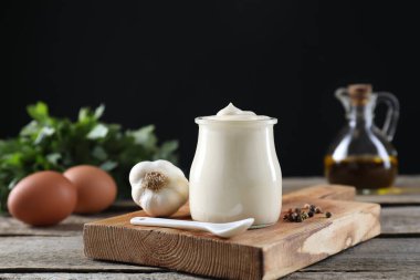 Cam kavanozda taze mayonez sosu ve ahşap masada malzemeler.