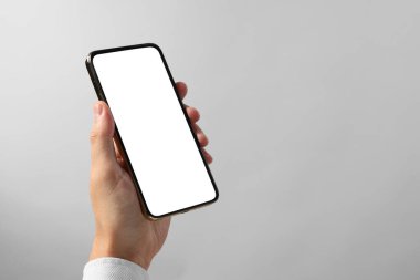 Elinde gri arka planda boş ekranlı akıllı telefon tutan adam, yakın plan. Tasarım için model