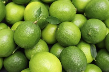 Arka plan olarak yeşil yapraklı bir sürü taze limon, üst görünüm