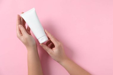 Pembe arka planda el kremi tüpü olan bir kadın. Metin için boşluk