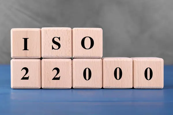 International Organization for Standardization. Cubes with abbreviation ISO and number 22000 on blue wooden table