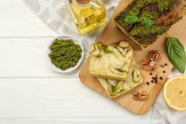 Taze pişmiş pesto ekmeği. Beyaz ahşap masada malzemeler var. Metin için boşluk