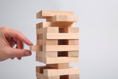 Açık gri arka planda Jenga oynayan kadın, yakın plan