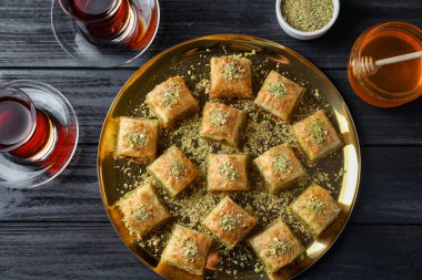 Siyah ahşap masada servis edilen, doğranmış fındıklı enfes taze baklava. Doğu tatlıları