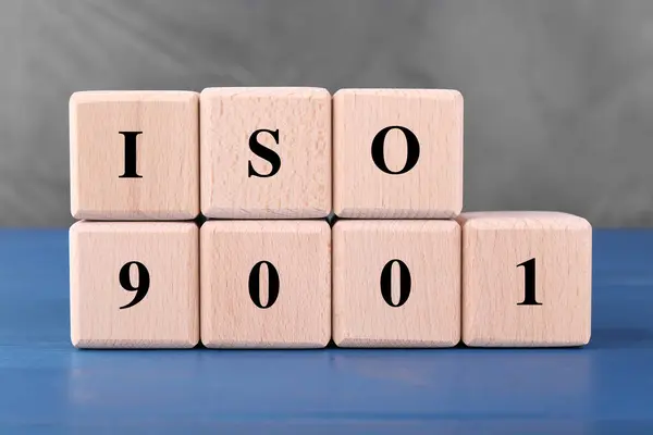 International Organization for Standardization. Cubes with abbreviation ISO and number 9001 on blue wooden table