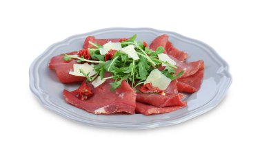 Bir tabak lezzetli bresaola salatası, güneşte kurutulmuş domates ve beyaz yalıtılmış parmesan peyniri.