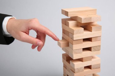 Açık gri arka planda Jenga oynayan kadın, yakın plan