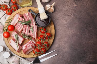 Düz kompozisyon, kesilmiş çiğ domuz kaburgası ve kahverengi masanın üzerine sos. Metin için boşluk