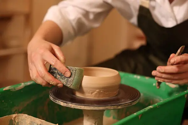 Clay crafting. Woman making bowl on potter's wheel indoors, closeup