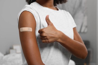 Aşıdan sonra kolunda bandaj olan genç bir kadın başparmağının içeride olduğunu gösteriyor.