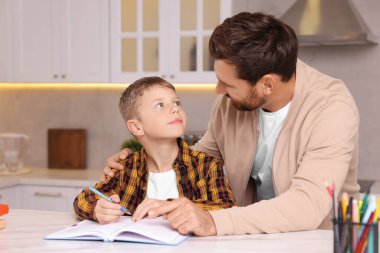 Disleksi sorunu. Baba oğluna mutfakta ödevlerinde yardım ediyor.
