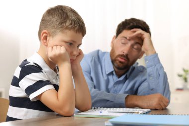 Disleksi sorunu. Sinirli baba oğluna ev ödevlerinde yardım ediyor, kapalı mekanlarda, seçici bir odak.