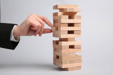 Açık gri arka planda Jenga oynayan kadın, yakın plan