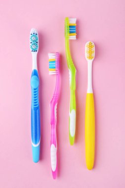 Pembe arka planda birçok farklı diş fırçası, düz yatış