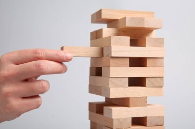 Açık gri arka planda Jenga oynayan kadın, yakın plan