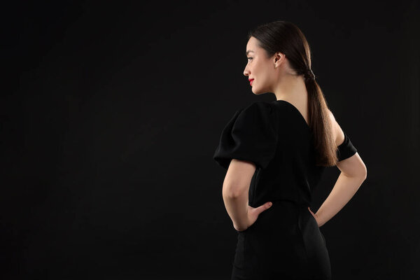 Beautiful young woman on black background, space for text