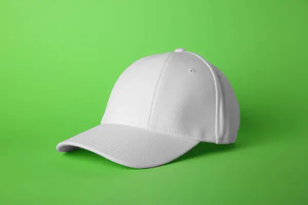 Stylish white baseball cap on light green background