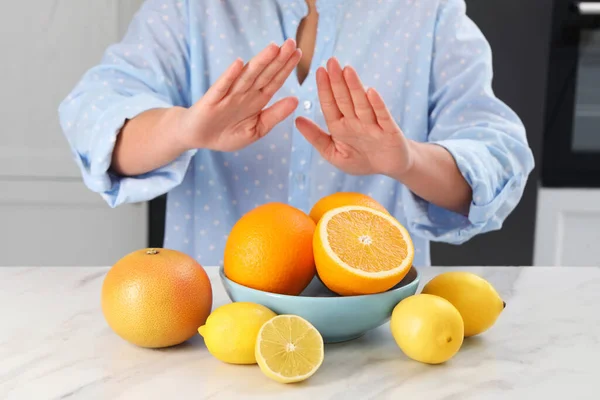Woman suffering from food allergies refusing eat citrus fruits at light marble table indoors, closeup