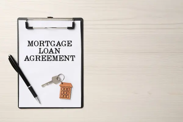 Mortgage loan agreement, house key and pen on white wooden table, top view. Space for text